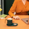 a girl using a laptop while coffee being heated in the mug warmer